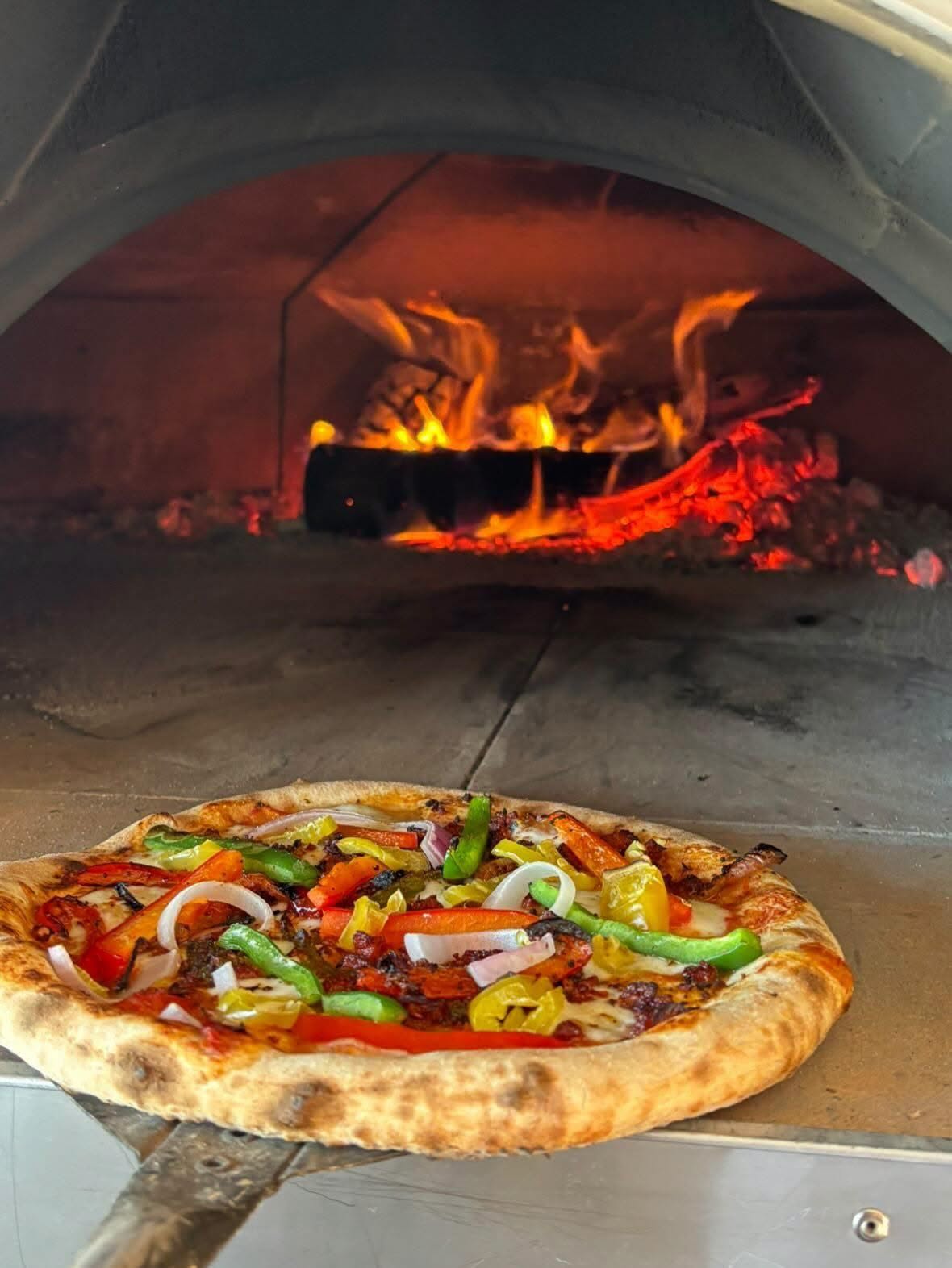 A Nite Owl artisan pizza at the mouth of the wood-fired oven